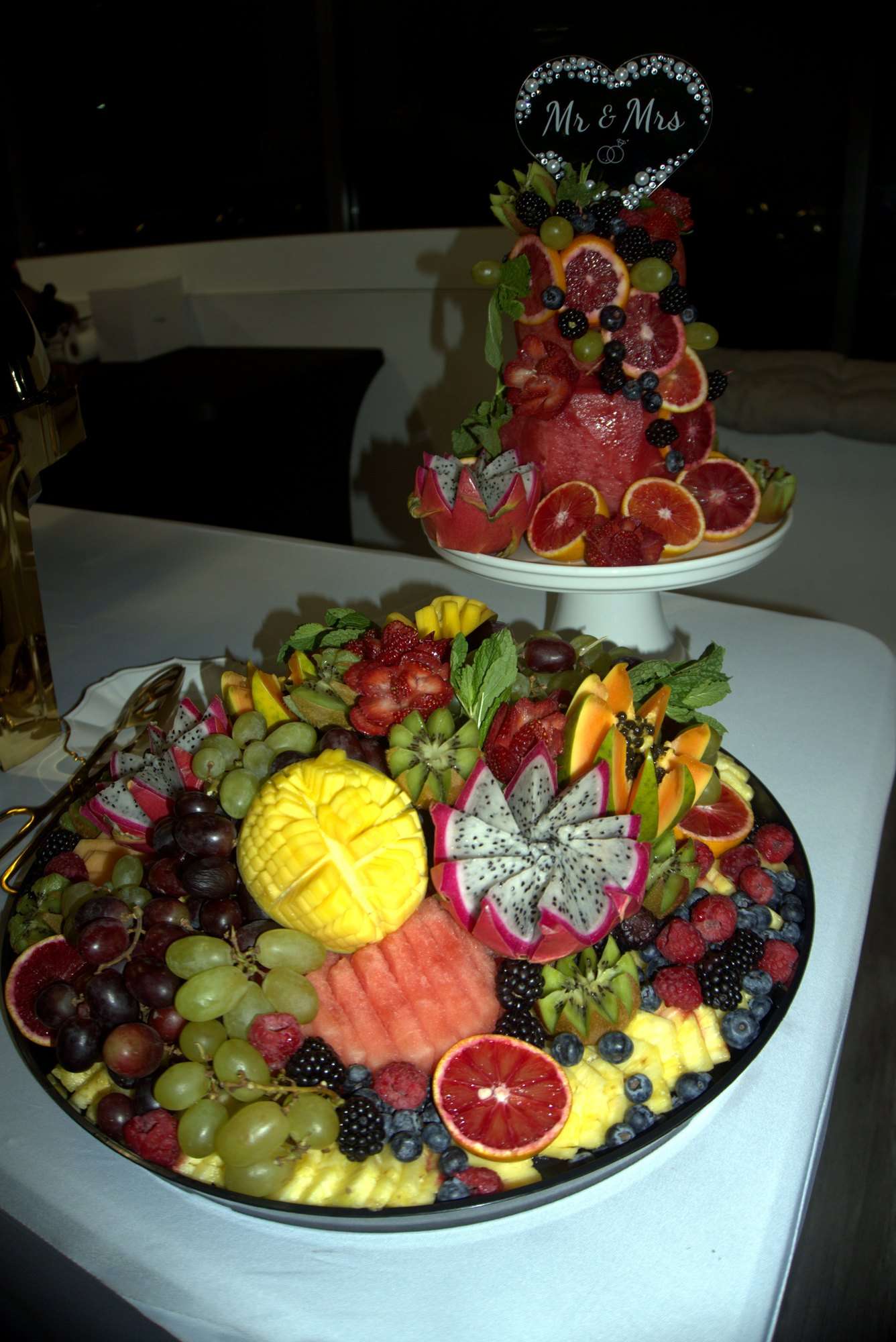 A large fruit platter with carved dragon fruit, mango, blood orange and berries at a wedding
