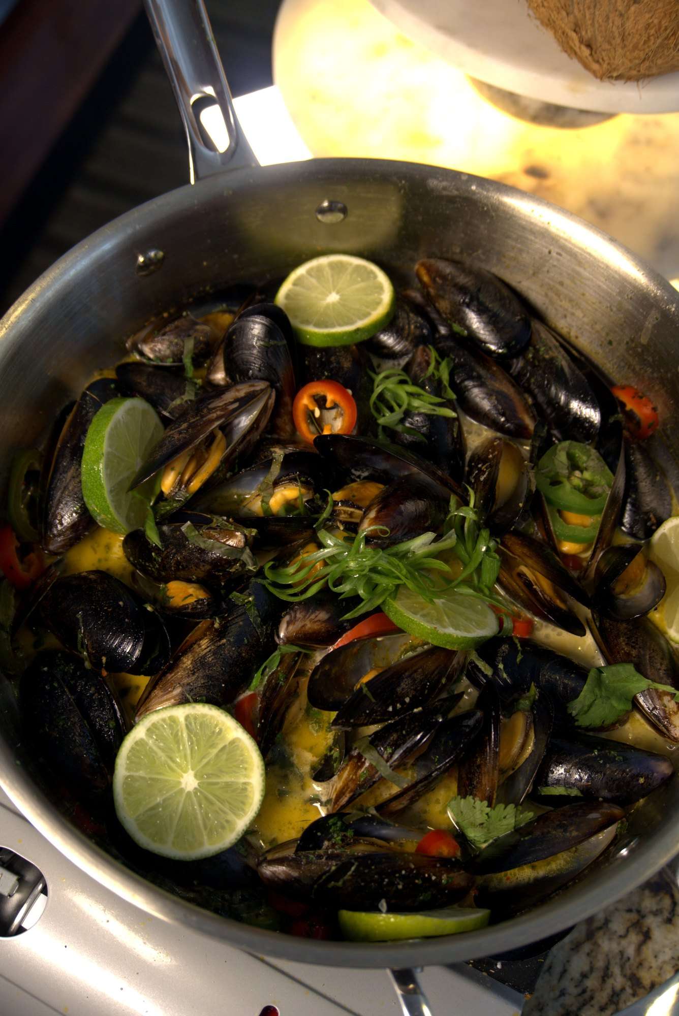Mussels in a steel pan with lime slices, chili and herbs