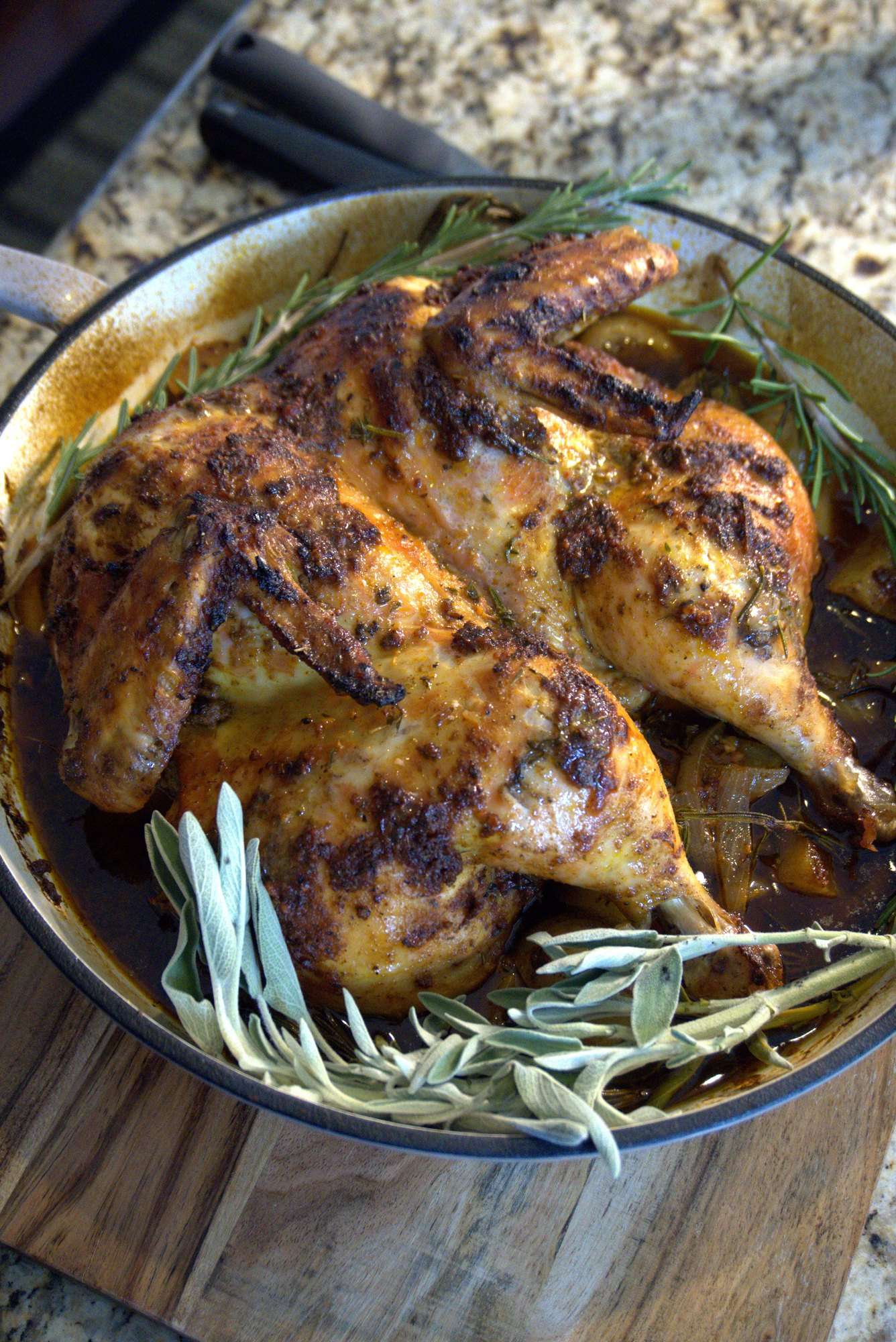 Spatchcocked roast chicken with rosemary and sage in a cast-iron pan