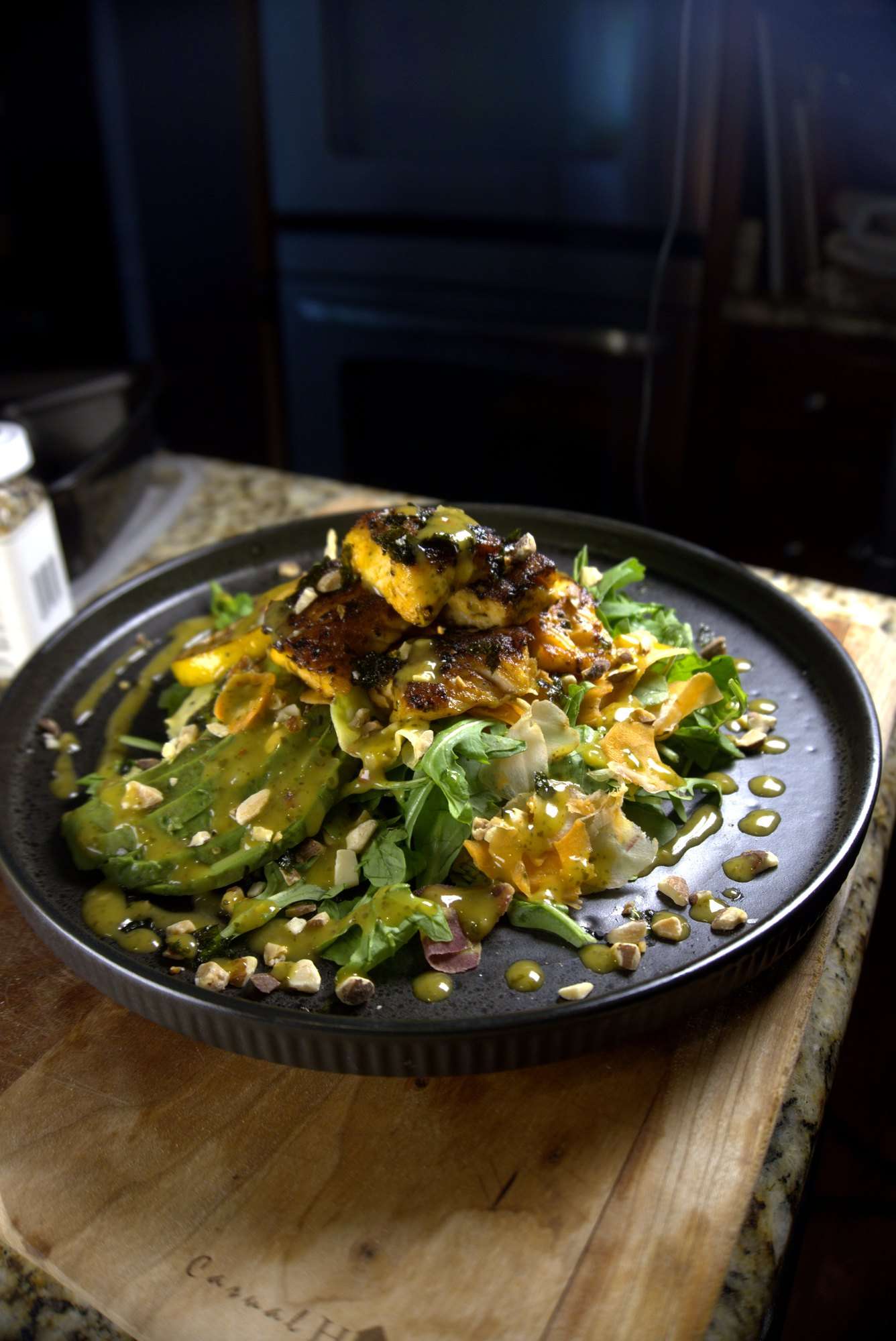 Blackened salmon over a green salad with avocado and toasted nuts
