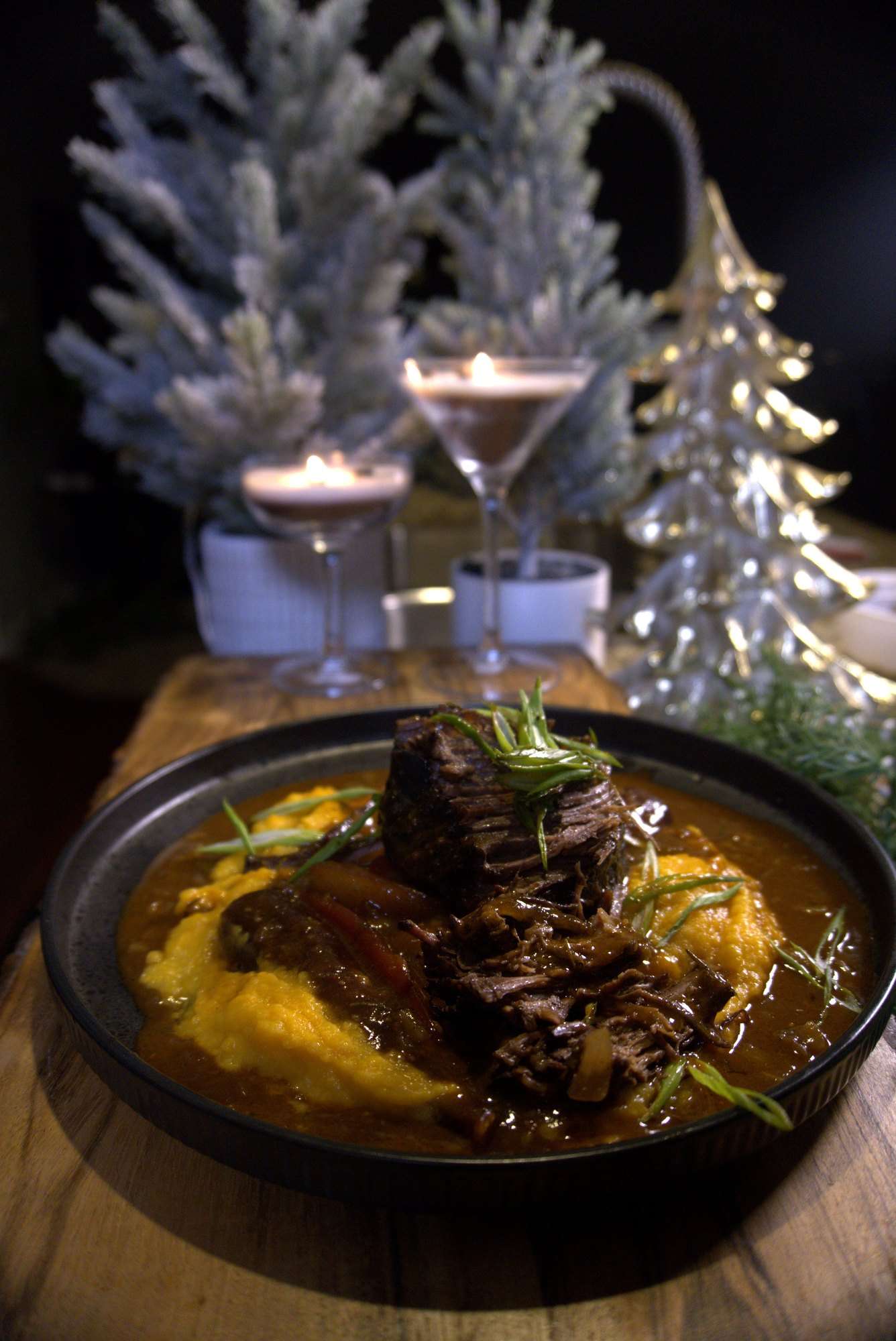 Braised short rib over creamy polenta, set on a candlelit holiday table