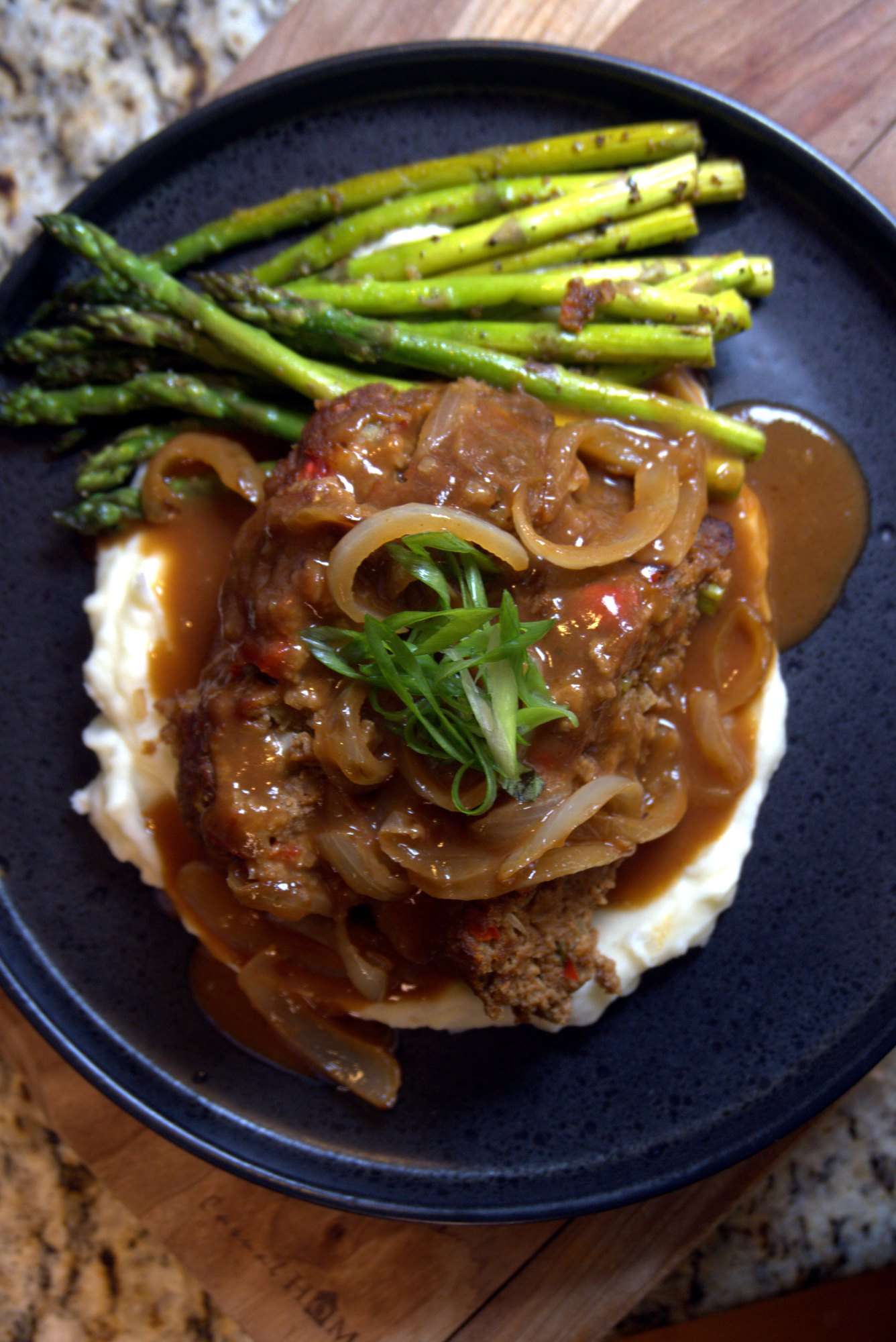 Smothered steak with onions and gravy over mashed potatoes, with grilled asparagus